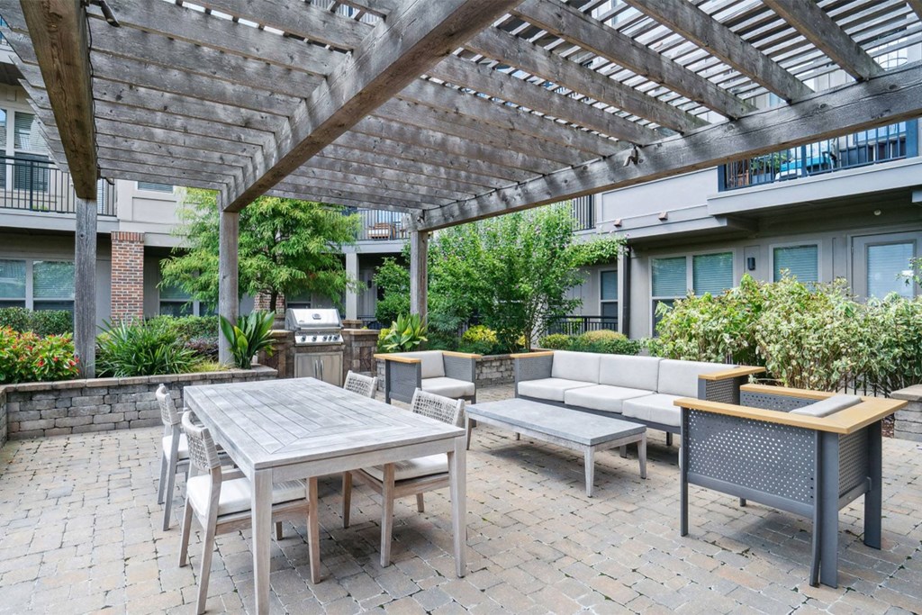 A patio with a table and chairs under a wooden pergola at The Linden Apartments, Davidson, North Carolina