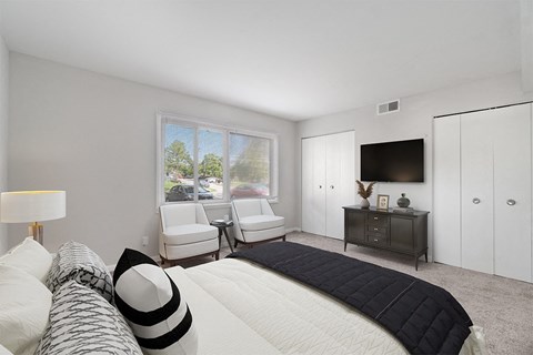 A bedroom with a large bed and a window with a view of trees and cars outside.