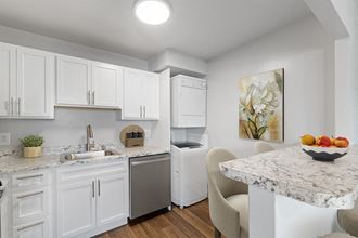 a kitchen and laundry room with white cabinets and marble countertops at Falls Village Apartments, Baltimore MD