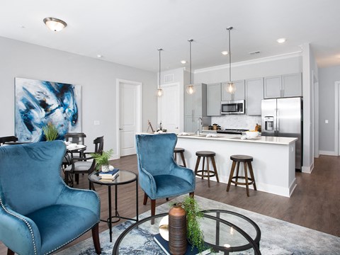 a living room with blue chairs and a kitchen with an island