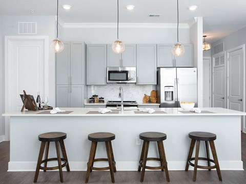 a kitchen with white cabinets and a bar with three stools