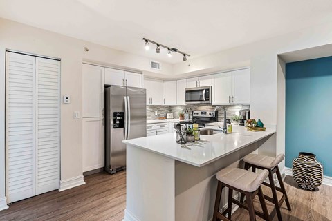 A kitchen with white cabinets and a white island with a bar stool.