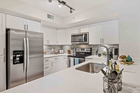 A modern kitchen with a stainless steel refrigerator and a white countertop.