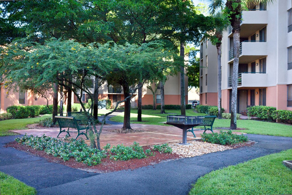 a park with benches and trees in front of an apartment building