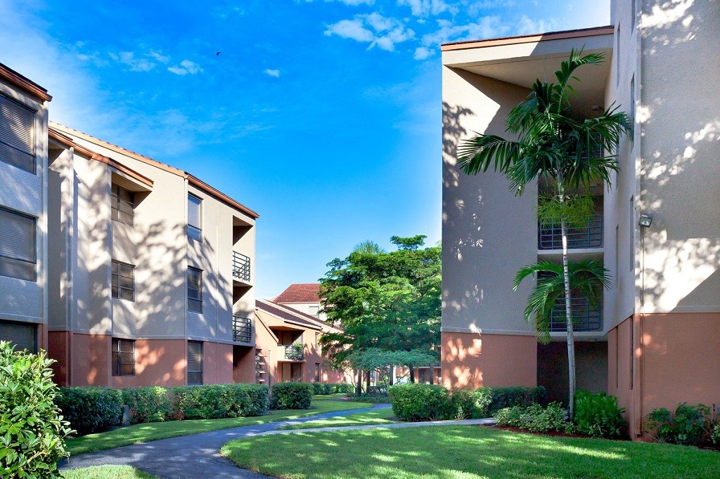 a pathway between two apartment buildings with grass and trees