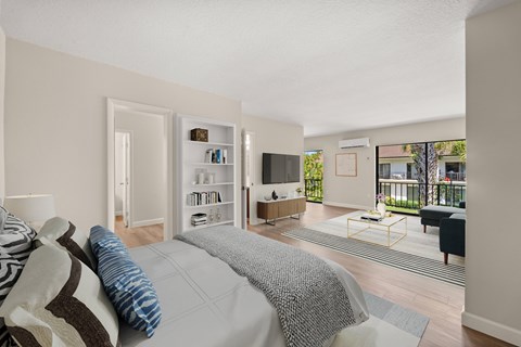 A bedroom with a large bed and a balcony overlooking the backyard.