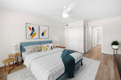 A bedroom with a bed, a ceiling fan, and two side tables.