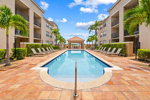 A swimming pool surrounded by lounge chairs and palm trees.