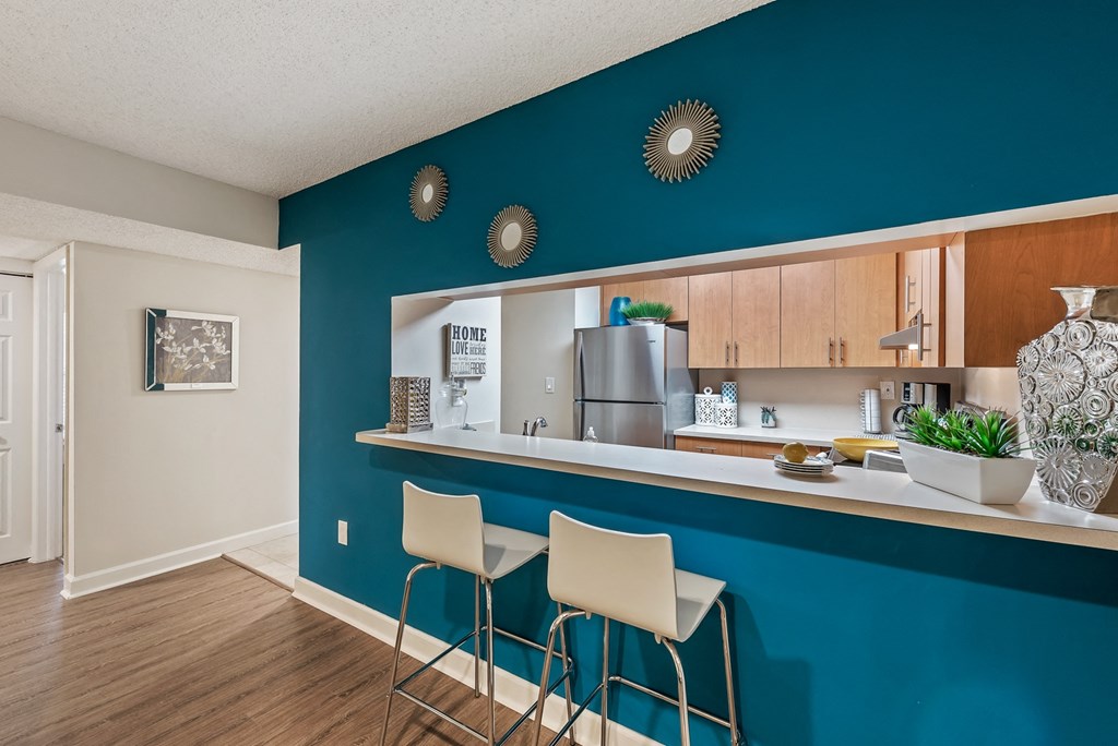 a kitchen with a blue wall and a bar with three stools