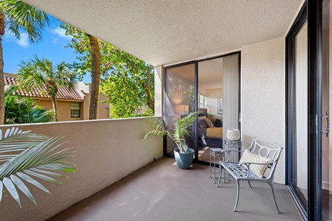 a balcony with two chairs and a potted plant