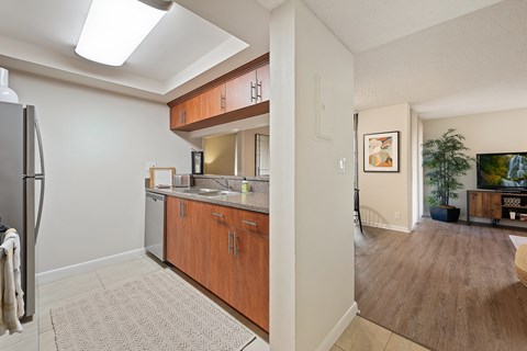 A kitchen with a refrigerator, sink, and cabinets.