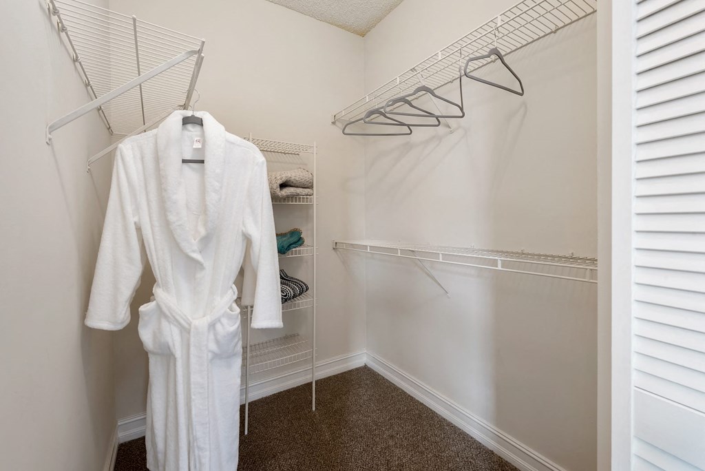 a walk in closet with a white robe and clothes rack