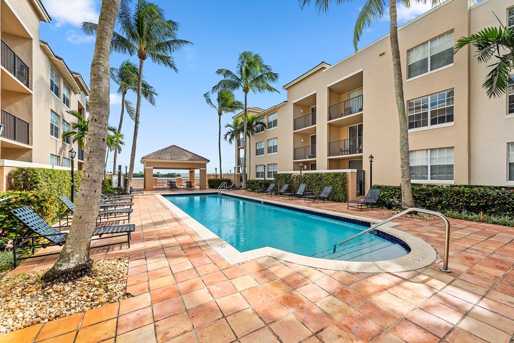 a swimming pool with palm trees in front of an apartment building