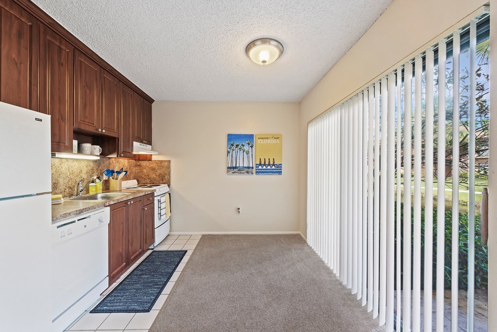 a kitchen with white appliances and wood cabinets and a large window
