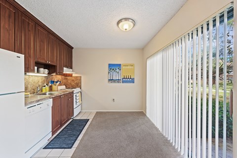 a kitchen with white appliances and wood cabinets and a large window