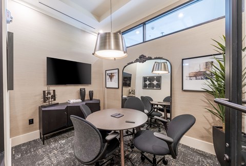 A conference room with a table, chairs, and a television.