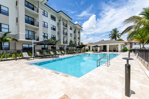 A large swimming pool in front of a building with a black umbrella.