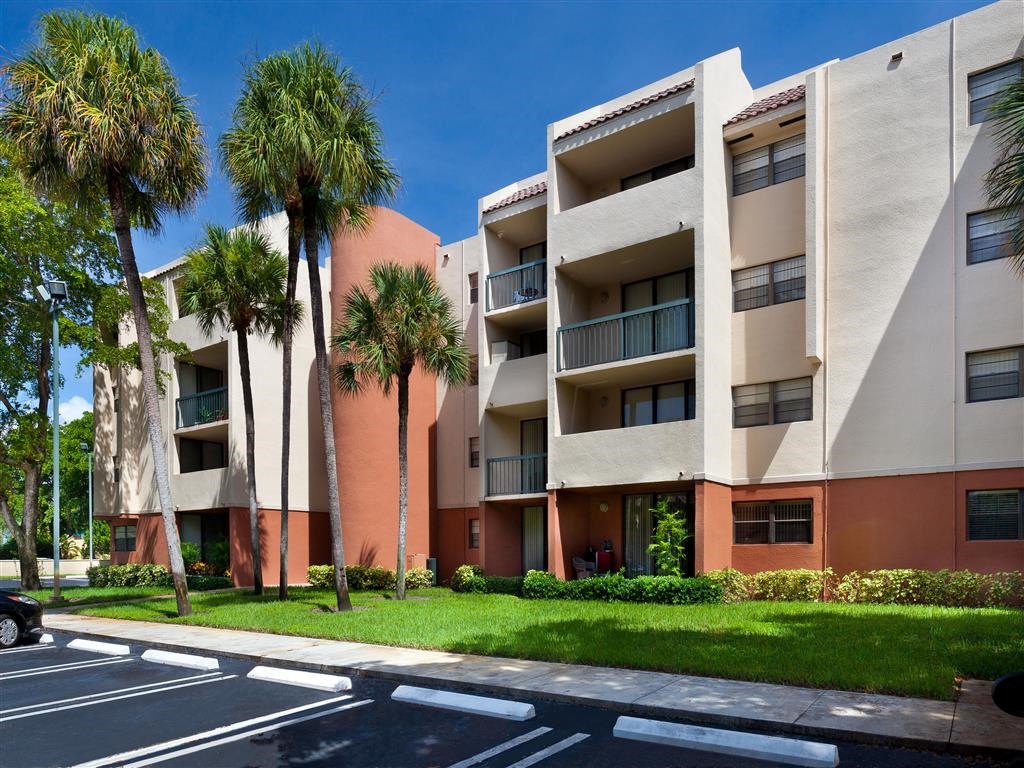 a street view of an apartment building with palm trees