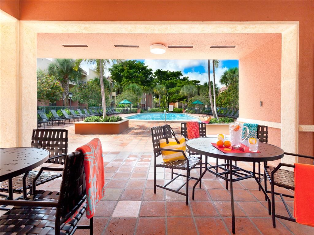 a patio with tables and chairs and a pool in the background