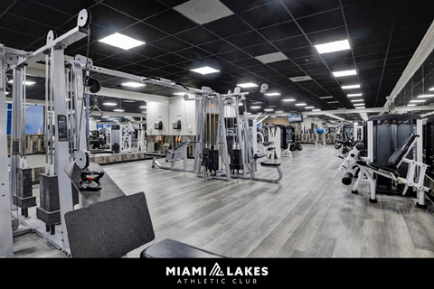 A gym with a variety of equipment inside the Miami Lakes Athletic Club.