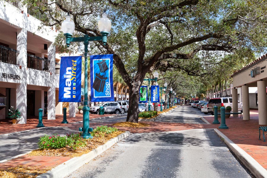 a street with buildings and trees and banners on street lamps