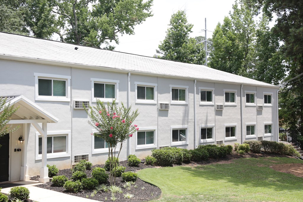 a large white building with a lawn and trees in front of it