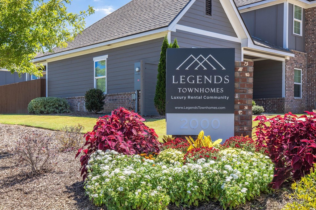 A house with a sign that says Legends Townhomes in front of it.