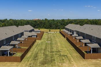 A large grassy field with a row of houses on either side.