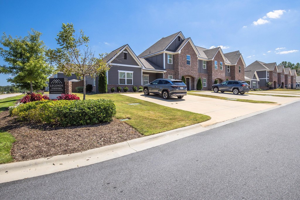 A row of houses with cars parked in front.