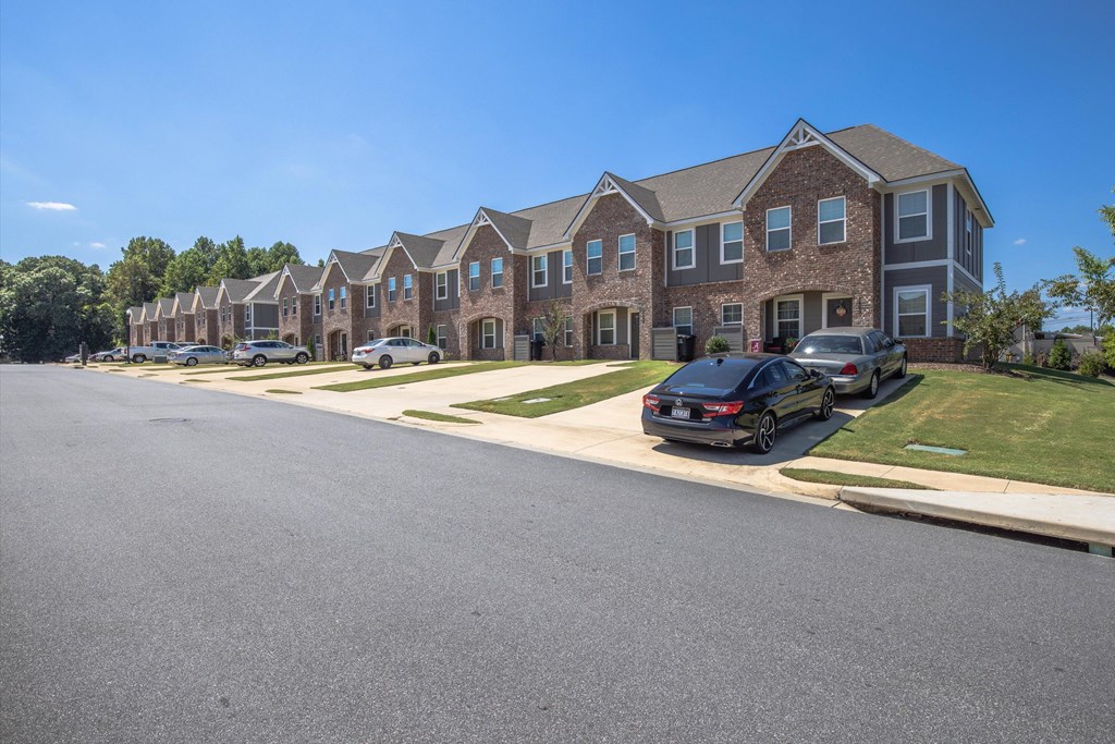 A row of houses with cars parked in front.