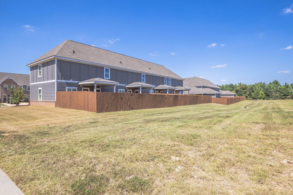 A large house with a grey roof and a brown fence.