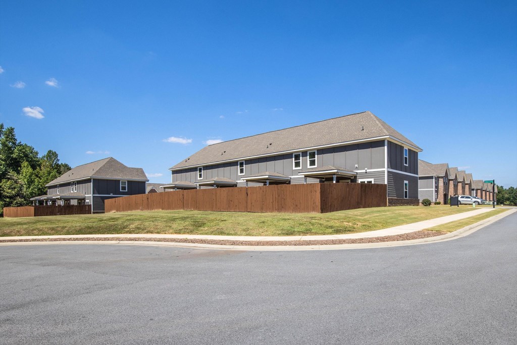 A row of houses with a grey roof and a brown fence.