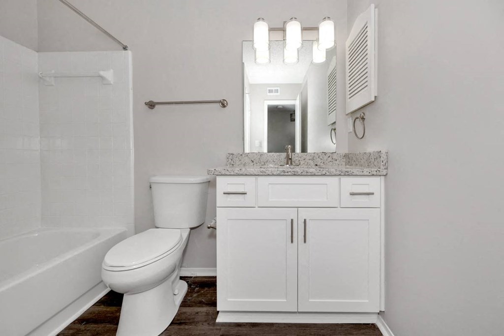 A white bathroom with a toilet, sink, and mirror.