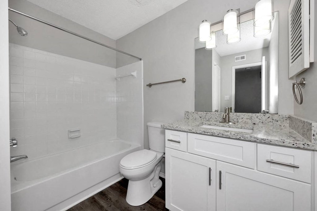 A white bathroom with a toilet, sink, and mirror.