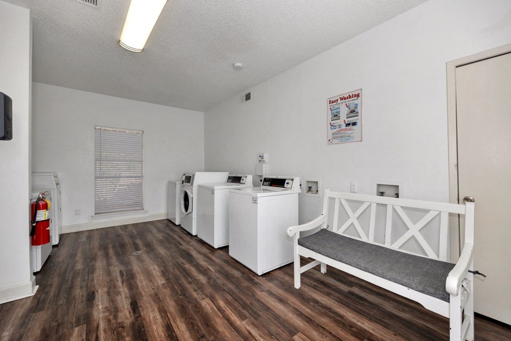 A laundry room with a washer and dryer, a bench, and a fire extinguisher.