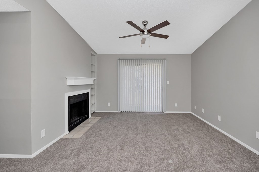 A spacious living room with a fireplace and a ceiling fan.