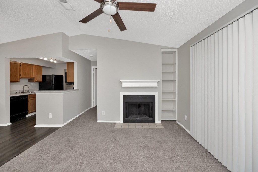 A living room with a fireplace and a ceiling fan.