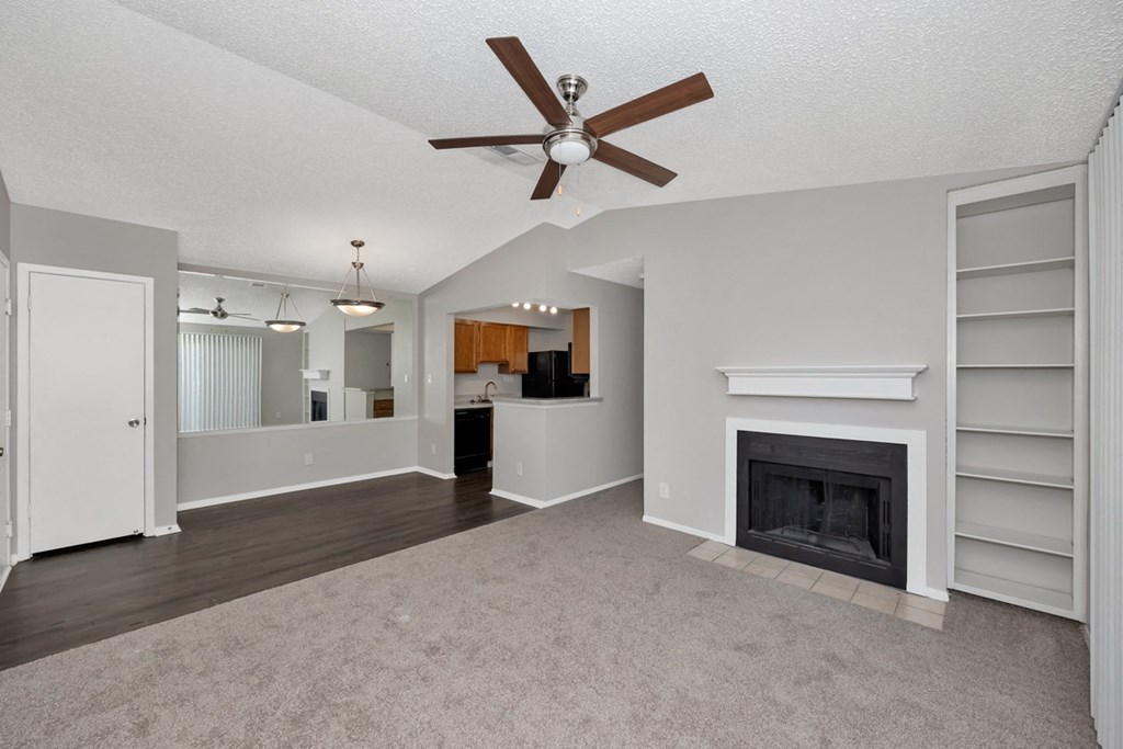 A spacious living room with a fireplace and a ceiling fan.
