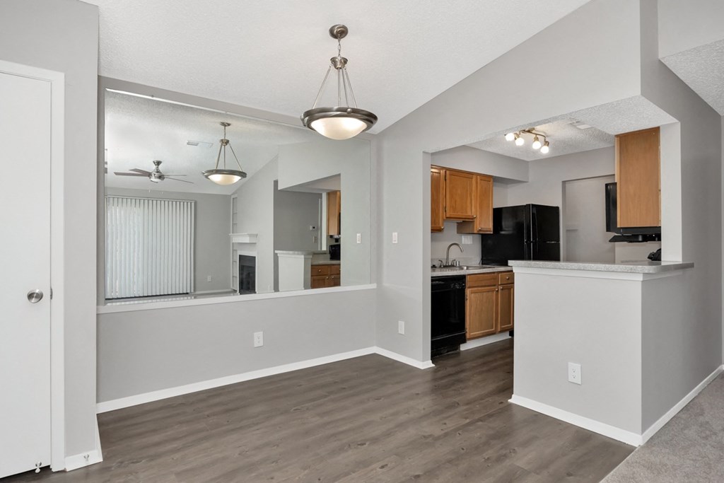 A well-lit, spacious kitchen and living room with wooden floors and white walls.