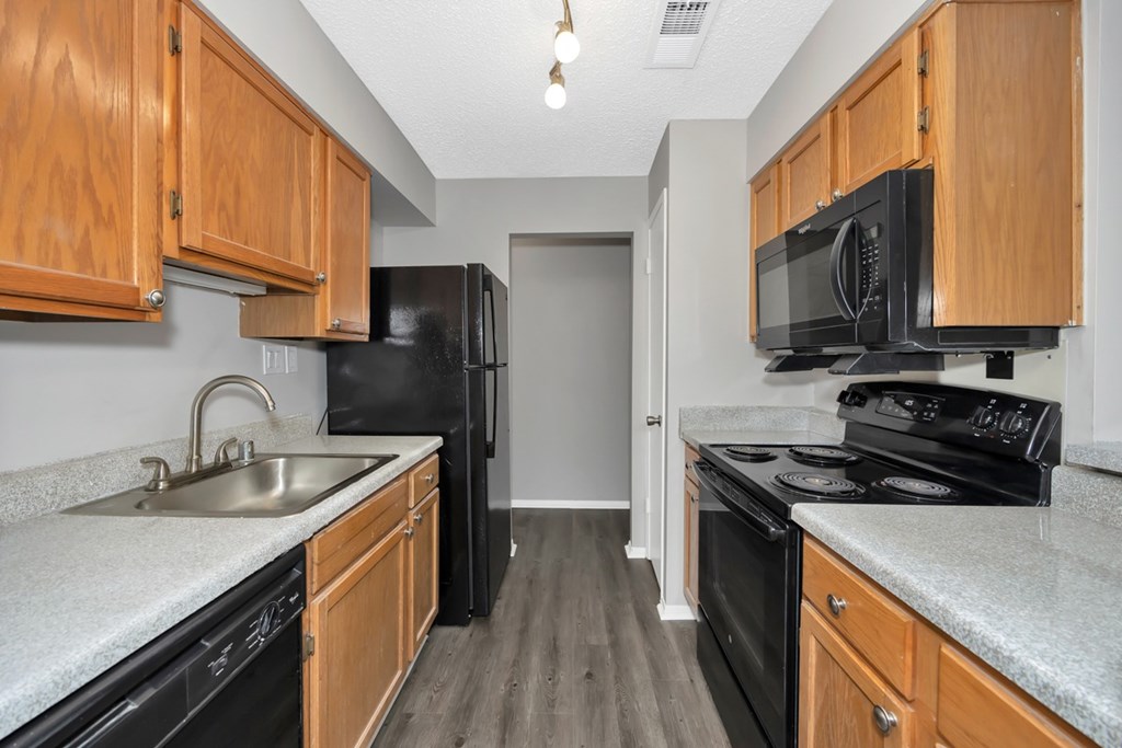A kitchen with black appliances and wooden cabinets.