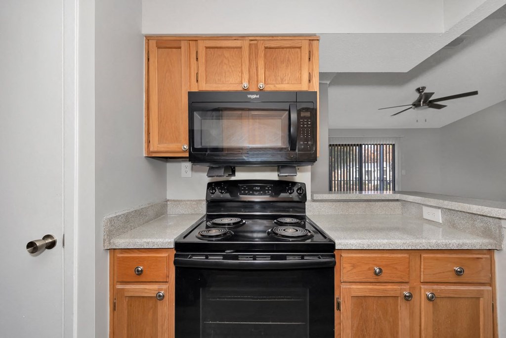 A black stove and microwave in a kitchen with wooden cabinets.