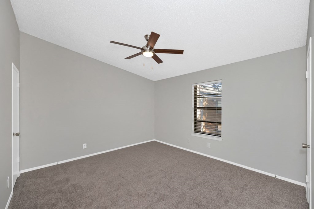 A room with a ceiling fan and carpeted floor.