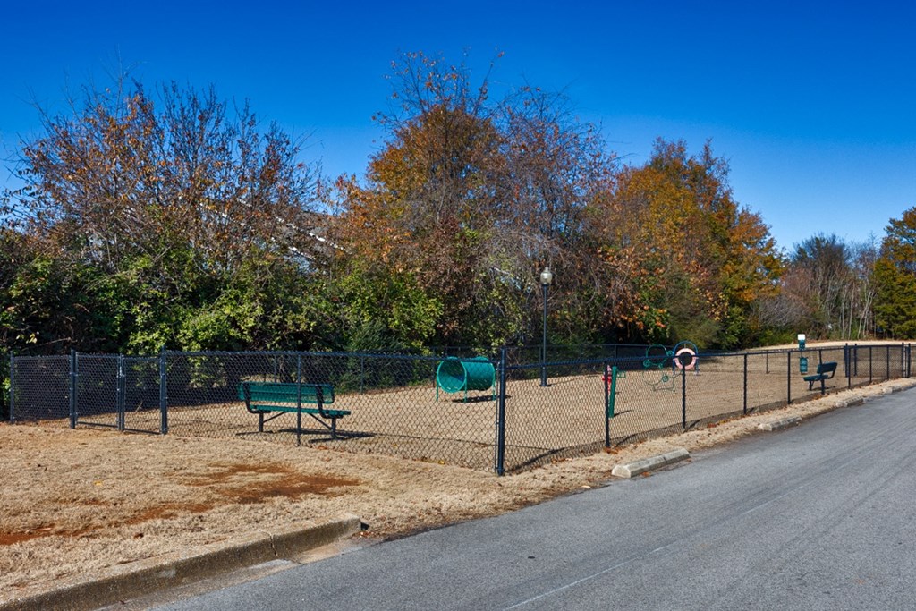 A park with a fence, bench, and trees.