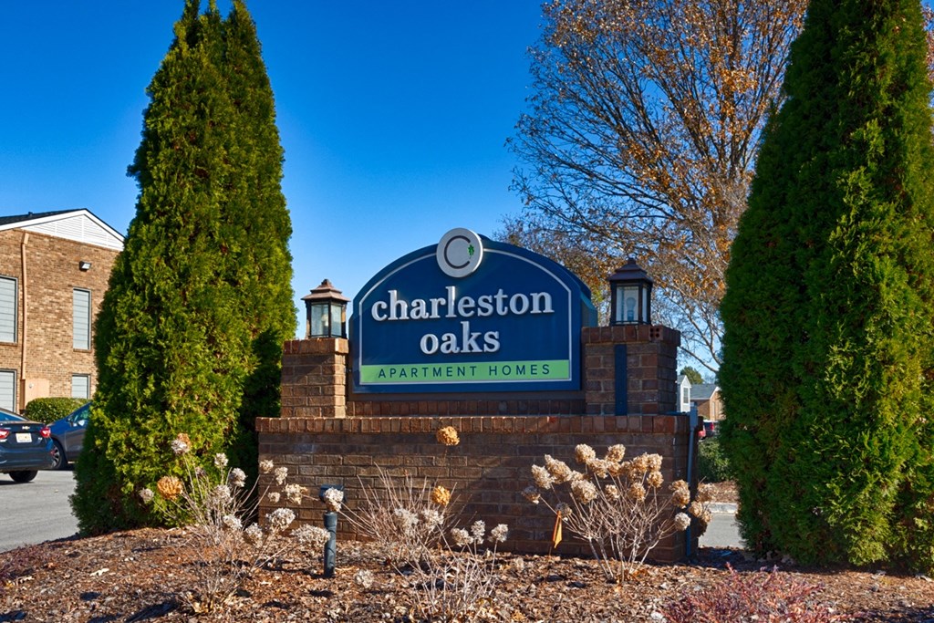 A sign for Charleston Oaks Apartment Homes is displayed in front of a building.