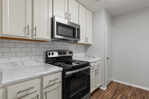 A kitchen with white cabinets and a black stove top oven.