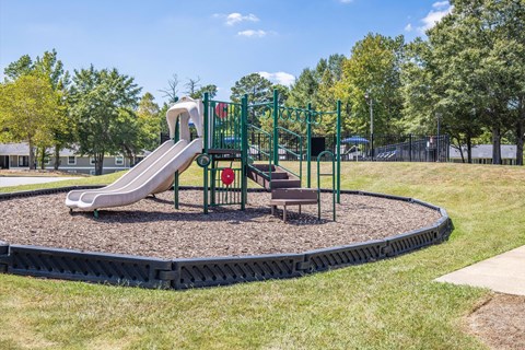 A playground with a green slide and a red sign.