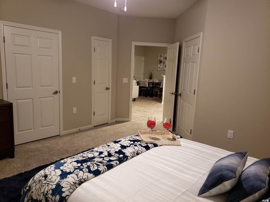 a bedroom with a bed and two glasses of wine