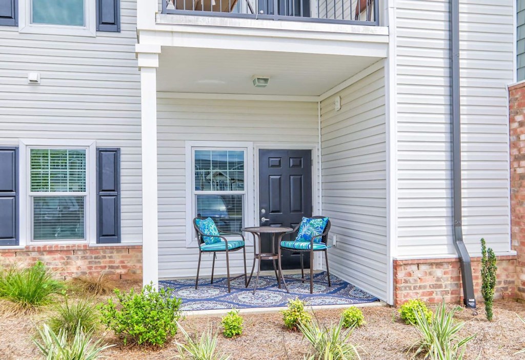 a patio with two chairs and a table in front of a house
