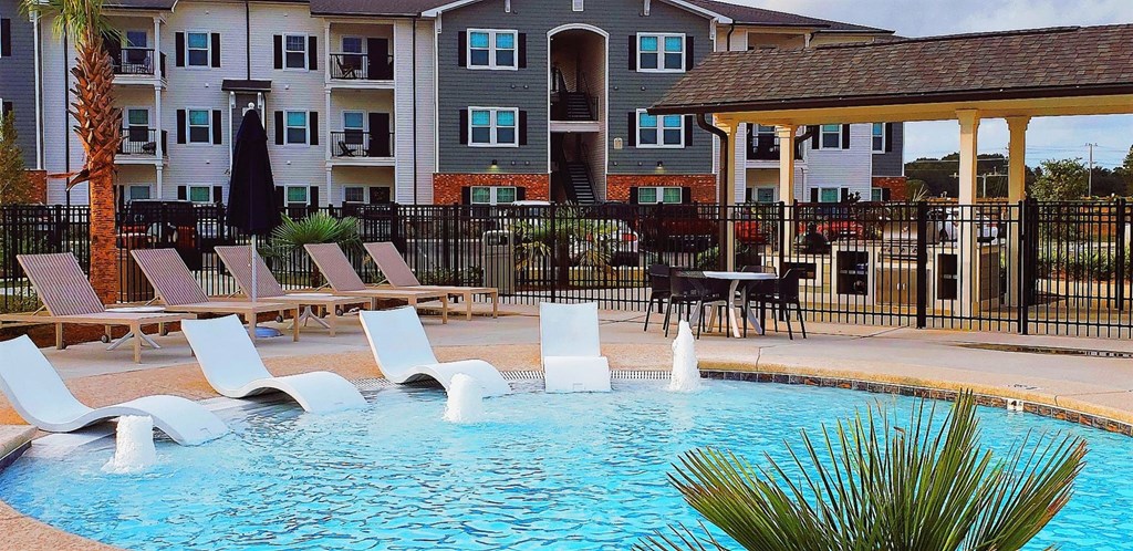 a swimming pool with chairs and a building in the background
