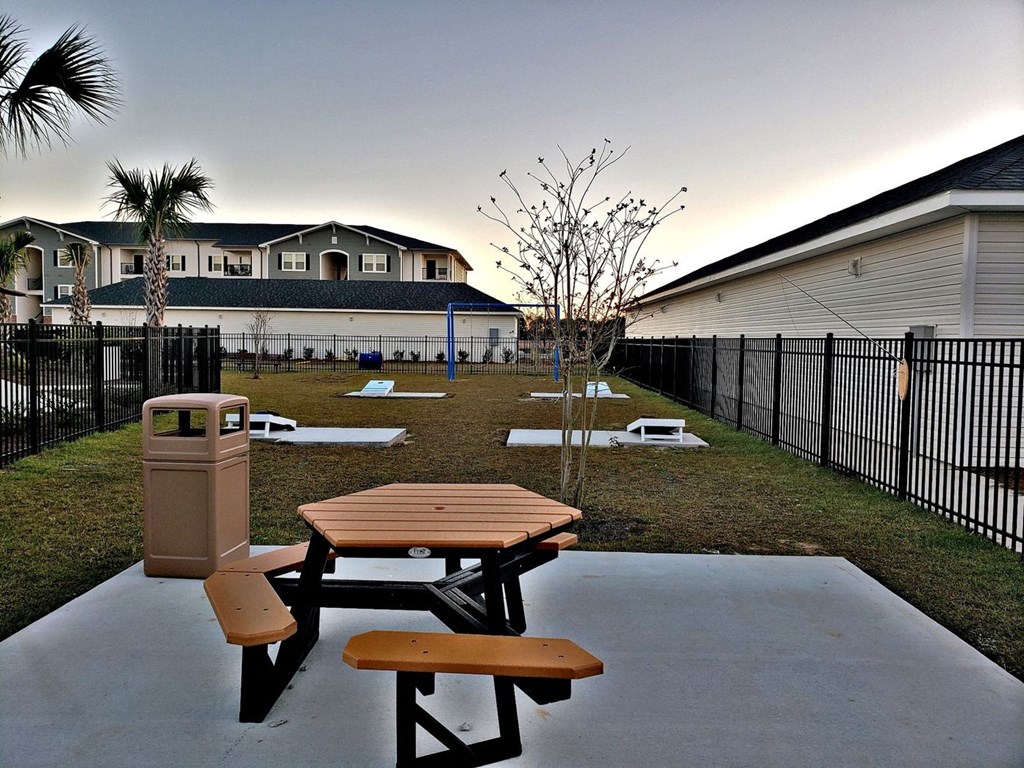 a picnic table and a trash can in a backyard